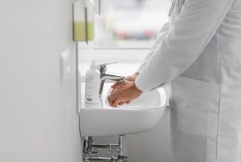 health care, hygiene and people concept - doctor washing hands at hospital sink. doctor washing hands at hospital sink