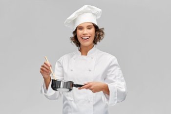 cooking, culinary and people concept - happy smiling female chef in toque with saucepan over grey background. happy smiling female chef with saucepan