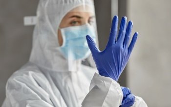health safety, medicine and pandemic concept - close up of female doctor or scientist in protective wear, medical mask, face shield and gloves for protection from virus disease. doctor in protective wear, mask and face shield