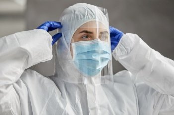 health safety, medicine and pandemic concept - close up of female doctor or scientist in protective wear, medical mask, face shield and gloves for protection from virus disease. doctor in protective wear, mask and face shield
