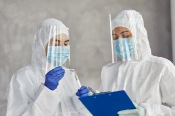 health safety, medicine and pandemic concept - female doctors or scientists in protective wear, medical masks, gloves and face shields with clipboard, test tube and cotton swab. doctors in medical mask and shield with clipboard