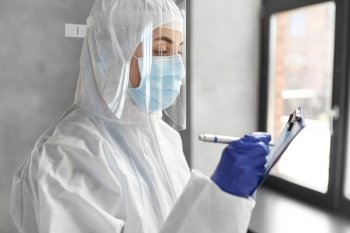 health safety, medicine and pandemic concept - close up of female doctor or scientist in protective wear, medical mask, gloves and face shield for protection from virus disease with clipboard. doctor in medical mask and shield with clipboard