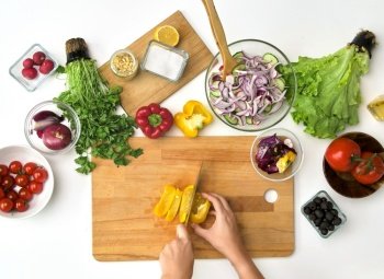 healthy eating, vegetarian food and cooking concept - POV shot of hands with knife chopping pepper on wooden cutting board for salad at kitchen. hands chopping pepper for salad at kitchen