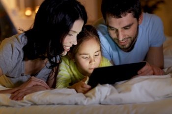 people and family concept - close up of happy mother, father and little daughter with tablet pc computer in bed at night at home. family with tablet pc in bed at night at home