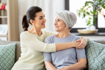 family, generation and people concept - happy smiling senior mother with adult daughter hugging at home. senior mother with adult daughter hugging at home