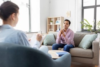 psychology, mental therapy and people concept - young indian man patient and woman psychologist at psychotherapy session. man and psychologist at psychotherapy session