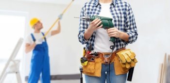 repair, construction and building concept - close up of woman or builder with working tools on belt with electric drill or perforator over painting works on background. woman or builder with drill and work tools