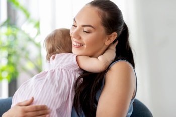 family, child and motherhood concept - portrait of happy smiling mother with little baby daughter hugging at home. happy mother hugging little baby daughter at home