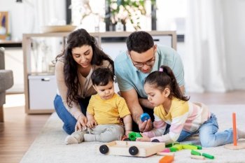 family and people concept - happy mother, father, little daughter and baby son playing with wooden toys at home. happy family palying with wooden toys at home