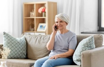 technology, communication and people concept - happy smiling senior woman calling on smartphone at home. senior woman calling on smartphone at home