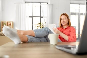 remote job, technology and people concept - happy smiling young woman with notebook and laptop computer at home office resting feet on table. woman with notebook and laptop at home office