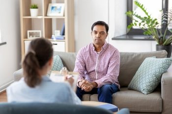 psychology, mental therapy and people concept - young indian man patient and woman psychologist at psychotherapy session. man and psychologist at psychotherapy session