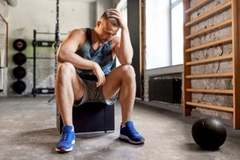 sport, bodybuilding, fitness and people concept - tired young man with medicine ball in gym. tired young man with medicine ball in gym
