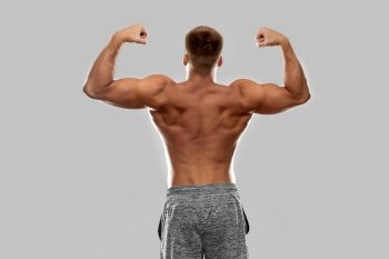sport, bodybuilding, fitness and people concept - young man or bodybuilder with bare torso showing his muscles. young man or bodybuilder with bare torso