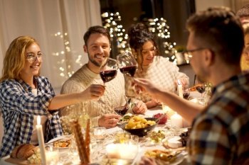 holidays, celebration and people concept - happy friends having christmas dinner party and drinking non-alcoholic red wine at home. happy friends drinking red wine at christmas party