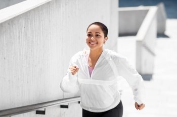 fitness, sport and healthy lifestyle concept - happy smiling young african american woman running upstairs outdoors. african american woman running upstairs outdoors