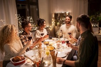 holidays, celebration and people concept - happy friends having christmas dinner at home drinking non-alcoholic red wine. happy friends drinking red wine at christmas party