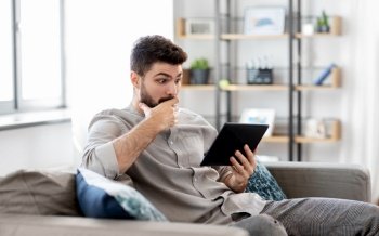 technology, people and lifestyle concept - shocked man with tablet pc computer at home. shocked man with tablet computer at home