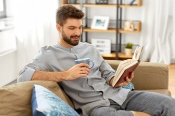 people and leisure concept - man reading book and drinking coffee at home. man reading book and drinking coffee at home