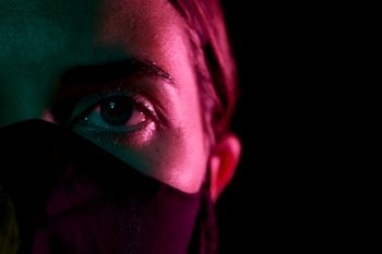 health, safety and pandemic concept - close up of young woman wearing reusable protective mask over black background. young woman wearing reusable protective mask