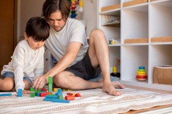 Little kid and his father playing at home with wood building blocks. Homeschooling. Stay at home. Family time