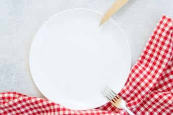 Abstract food background - empty white plate with red and white napkin and fork and knife. Abstract food background