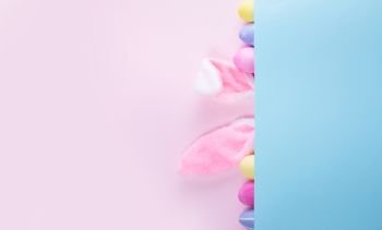 Easter rabbit flaffy ears and colored easter colored eggs on pink and blue background banner with copy space. Easter scene with rabbit ears