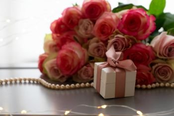 Rose fresh flowers bouquet on gray table by the window with pink heart gift box present. fresh rose flowers on gray