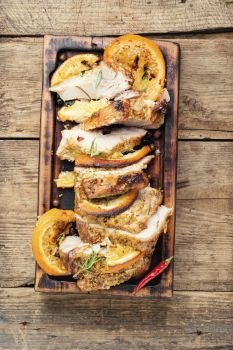 Sliced pork meat stuffed with oranges.Roasted meat on the kitchen board.. Baked meat in oranges
