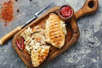 Roasted chicken breast stuffed with cheese, seasonings and sauce on the kitchen board. Grilled healthy chicken breasts
