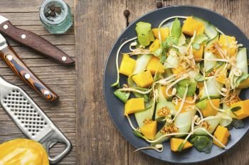 Vitamin spring salad with mango, cucumber and sprouts on old wooden table. Vegetable fruit salad with sprouts