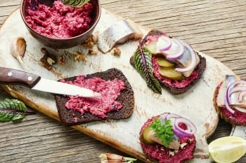 Small sandwiches or bruschettas with salted herring, beetroot and onions. Bruschetta with salted herring