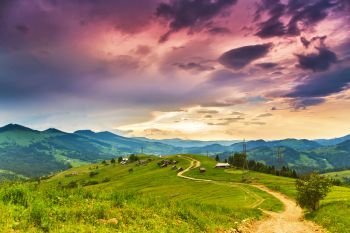 Summer mountain rural landscape, awesome evening sunset view on village and meadow. Colorful evening in mountain valley. Beauty of nature background. Europe travel, Carpathians, Ukraine. 