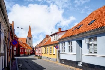 Streets of a small danish village with red rooftops in the summer sun under a blue sky