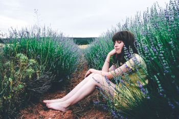 Young brunette woman sitting surrounded by lavender