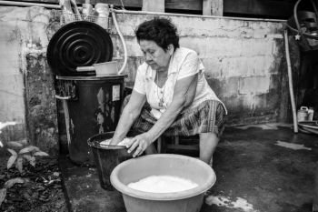Black and white image of Senior asian woman washing cloths by hand