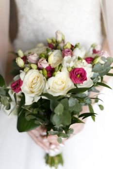 Beautiful wedding bouquet in hands of the bride. Shallow depth of field.