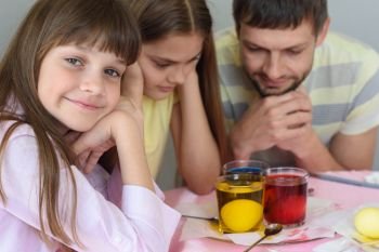 The family waits until the eggs are painted in a glass with dyes, the girl cheerfully looked into the frame