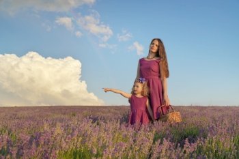 Little girl and mother at meadow of lavender. Family care and nature composition.