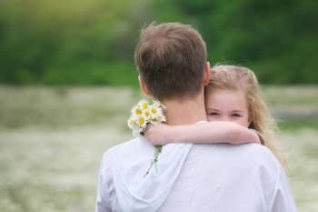 Father and daughter in big camomile mountain meadow. Emotional, love and care scene.