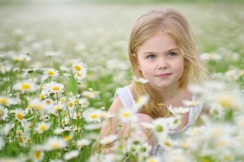 Cute little girl in big camomile meadow. Portrait composition.