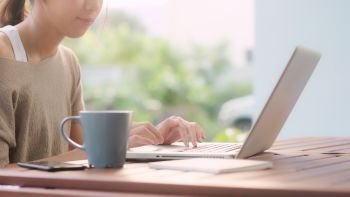 Freelance Asian woman working at home, business female working on laptop sitting on table in the garden in morning. Lifestyle women working at home concept.
