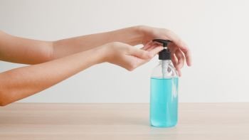 Asian woman using alcohol gel hand sanitizer wash hand for protect coronavirus. Female push alcohol bottle to clean hand for hygiene when social distancing stay at home and self quarantine time.