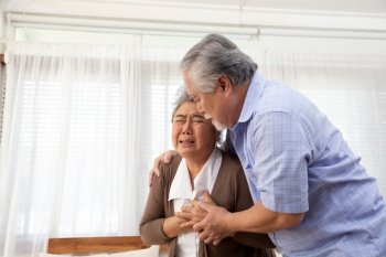 Asian senior woman with pain on heart on sofa in living room and take care by her husband, Health problem and feeling sick