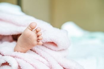 Newborn baby feet on a white blanket.
