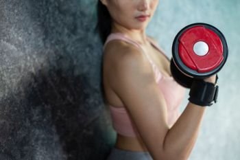 Woman standing exercising with a red dumbbell in the gym.