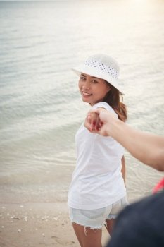girlfriend take her boyfriends to the beach. Woman holding his man hand to enjoy the beach. Relaxing holiday couple in love.