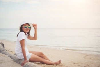 Young beautiful woman sitting on the beach wearing sunglasses. Freedom enjoy holiday, Women lifestyle concept.