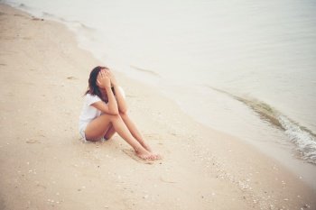 Young woman with looks lonely feel sit on the beach. Sad woman alone.