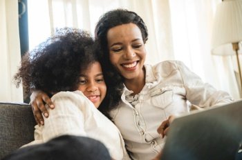 African American children watching on laptop, education at home with mom